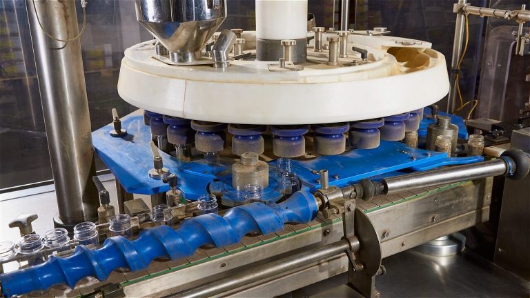 Picture of a rotary filling machine with empty jars on a conveyor