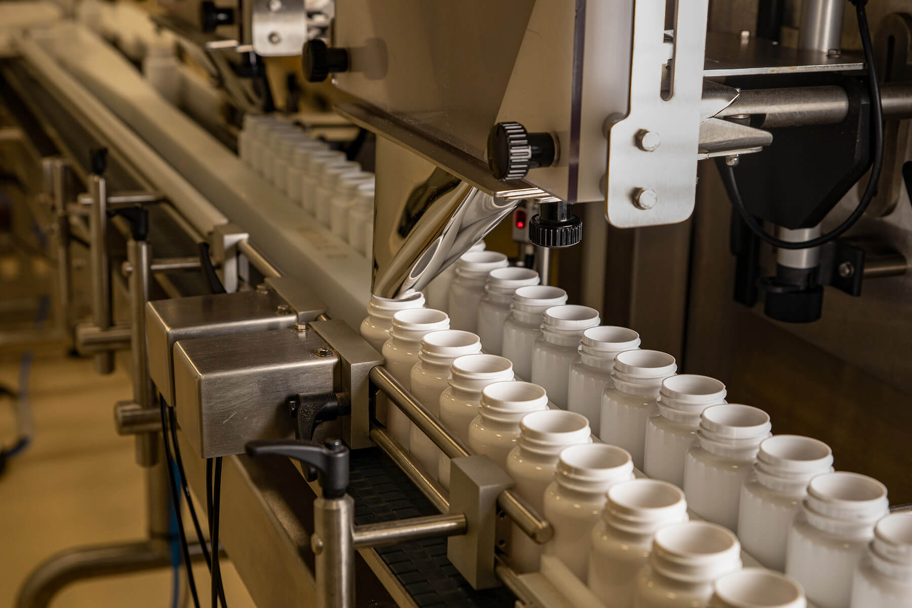 Tablet counting machine with white jars on a conveyor
